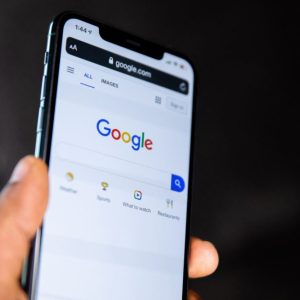 Mão segura celular na página do Google
