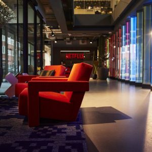 Duas poltronas vermelhas em destaque no primeiro plano da foto de um dos suntuosos escritórios da Netflix. Este é em Amsterdã, na Holanda.