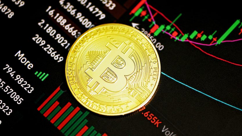 Foto de Bitcoin com cotações do mercado de ações ao fundo