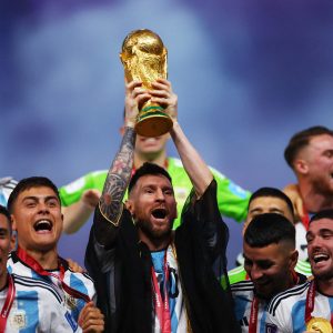 Copa do Mundo de Futebol FIFA 2022, Argentina é tricampeã mundial de futebol em decisão por pênaltis, Na foto, o argentino Lionel Messi levanta o troféu da Copa do Mundo ao lado de companheiros de equipe enquanto comemoram após a vitória na Copa do Mundo