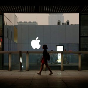 Imagem de uma pessoa caminhando em frente à loja da Apple.