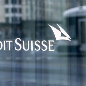 Foto de logo do banco Credit Suisse sobre uma parede de vidro.
