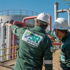 Foto de dois funcionários da 3R Petroleum, vestindo uniforme verde e capacete branco. As ações da 3R (RRRP3) lideraram bloco de altas no Ibovespa em 17/05/2024