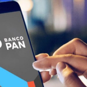 Foto de uma mão mexendo em um celular com o aplicativo do Banco Pan (BPAN4) aberto.
