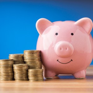 Foto para matéria sobre quanto rendem 400 mil na poupança em que aparece um cofrinho em formato de porco com várias moedas ao lado.