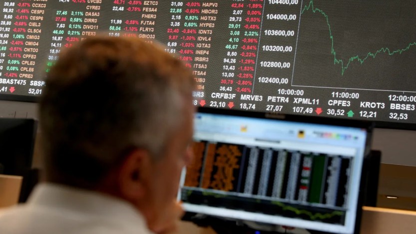 Foto de um investidor observado os painéis da bolsa de valores do Brasil, a B3. A matéria aponta as ações mais líquidas da bolsa com maior rendimento em dividendos.