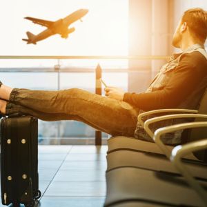 Homem espera com pés sobre mala voo em aeroporto