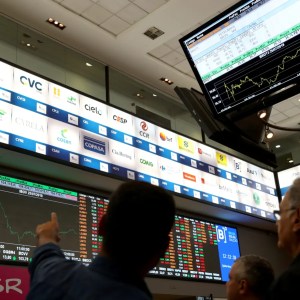 Foto de operadores da bolsa de valores apontando para o painel de negociação na sede da B3. A matéria mostra como montar uma carteira de dividendos com base em ações