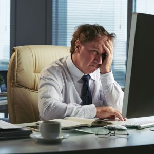 Homem olhando para o computador com cara de tristeza simbolizando os investidores diante da queda da bolsa