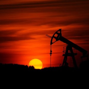 Foto de uma jazida de petróleo e um pôr do sol; a matéria descreve o movimento de alta do petróleo e o impacto nas ações da Petrobras (PETR3, PETR4)