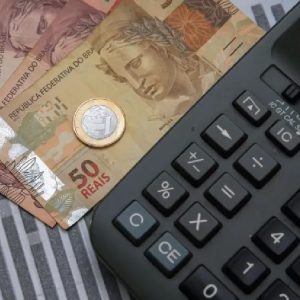 Notas e moedas de real ao lado de uma calculadora