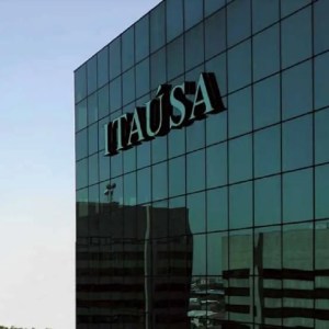Foto de um prédio de vidro com o logo da Itaúsa (ITSA4). A matéria lista ações que pagam dividendos e JCP em outubro