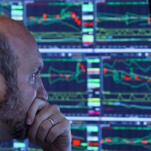 Foto de um homem olhando gráficos da bolsa de valores. A matéria descreve as ações que mais se valorizaram nos últimos 5 anos