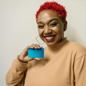 Mulher negra feliz e sorridente segurando um cartão de crédito