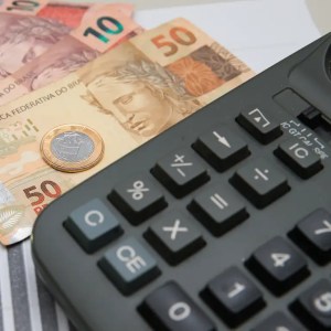 Foto com cédulas e moeda de Real para ilustrar matéria sobre quanto rendem R$ 500 mil na LCI