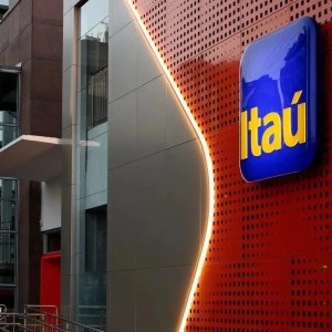 fachada de uma unidade do banco Itaú, com uma parede laranja e uma placa azul com o nome do banco em amarelo.