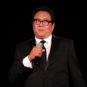 Robert Kiyosaki, autor de “Pai Rico, Pai Pobre”, veste terno preto e segura um microfone