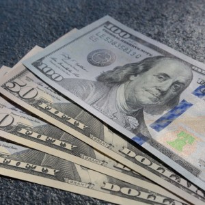 Imagem para a matéria sobre quanto rende US$ 1 mil em que aparecem 4 cédulas de dólar nos valores de 50 dólares e 100 dólares.