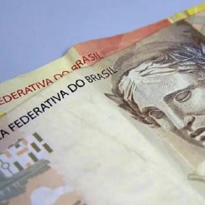 Imagem mostra, em foco, duas cédulas, sendo uma de 50 reais e outra de 20 reais. Onde investir R$ 50 por mês