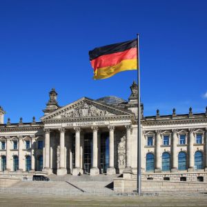 Imagem para a matéria sobre estudar na Alemanha em que aparece o prédio do Parlamento Alemão e algumas bandeiras do país