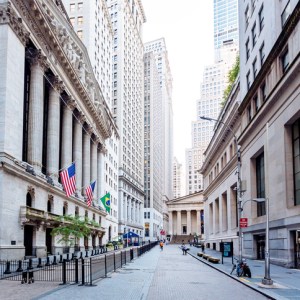 Foto mostra Wall Street e a Bolsa de Valores de Nova York para ilustrar conteúdo sobre investimentos, entre eles, a bolsa de mercados emergentes 