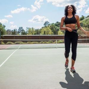 Imagem para o texto sobre mulher no esporte em que aparece uma mulher negra em uma quadra de tênis segurando uma raquete.