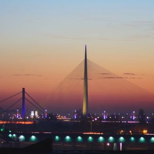 Texto sobre as cidades mais baratas da europa em que aparece a cidade de Belgrado com uma ponte ao pôr do sol