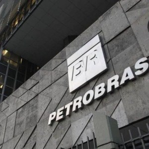 Foto de um prédio cinza e uma placa prateada com um escrito "Petrobras".
