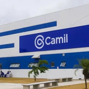 Imagem da fachada de uma das fábricas da Camil (CAML3): um prédio branco com algumas faixas azuis e o logo da empresa.