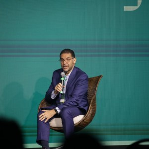 Foto de Mansueto Almeida, economista-chefe do BTG Pactual. Ele é homem, veste um terno azul escuro e fala ao microfone sentado em palestra.