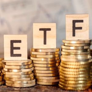 Imagem para matéria sobre melhores ETFs em que aparecem várias pilhas de moedas e em cima de três pilhas um bloco em cada com as letras E T F