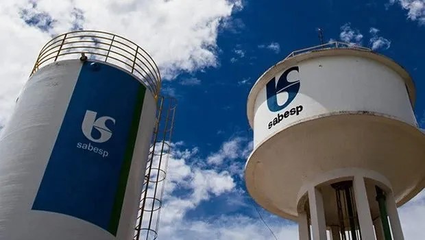 Foto de uma torre e de uma caixa de água da Sabesp (SBSP3). A matéria analisa dividendos a serem pagos por ação da empresa na bolsa