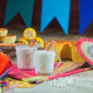 Imagem para matéria sobre comidas de festa junina em que aparece uma mesa com várias comidas, como bolo, espiga de milho, canjica, entre outros.