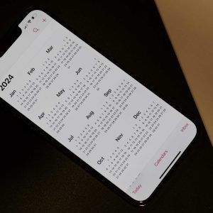 Imagem para texto sobre feriado 9 de julho em que aparece um celular em cima deu ma mesa preta com o calendário de 2024 aberto.